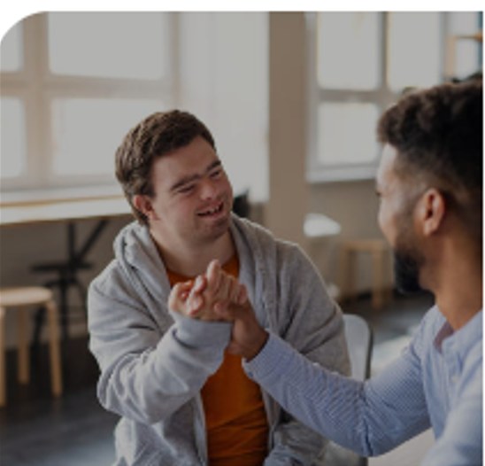 A young man with Down syndrome joyfully sharing a high-five with his support worker